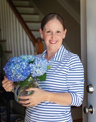 Megan standing near door with vase of flowers