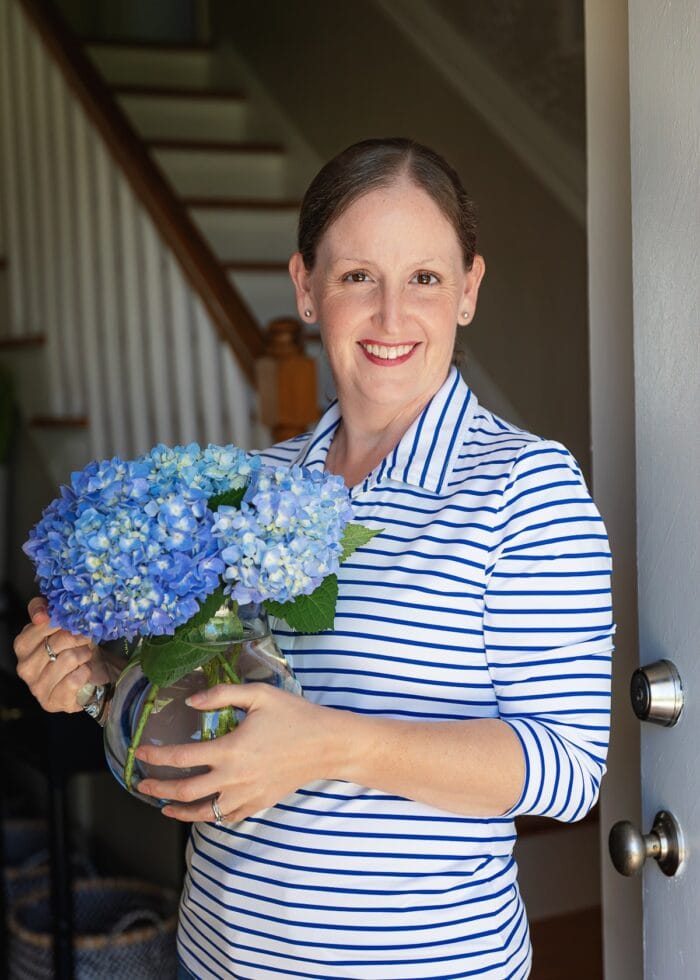 Megan standing near door with vase of flowers