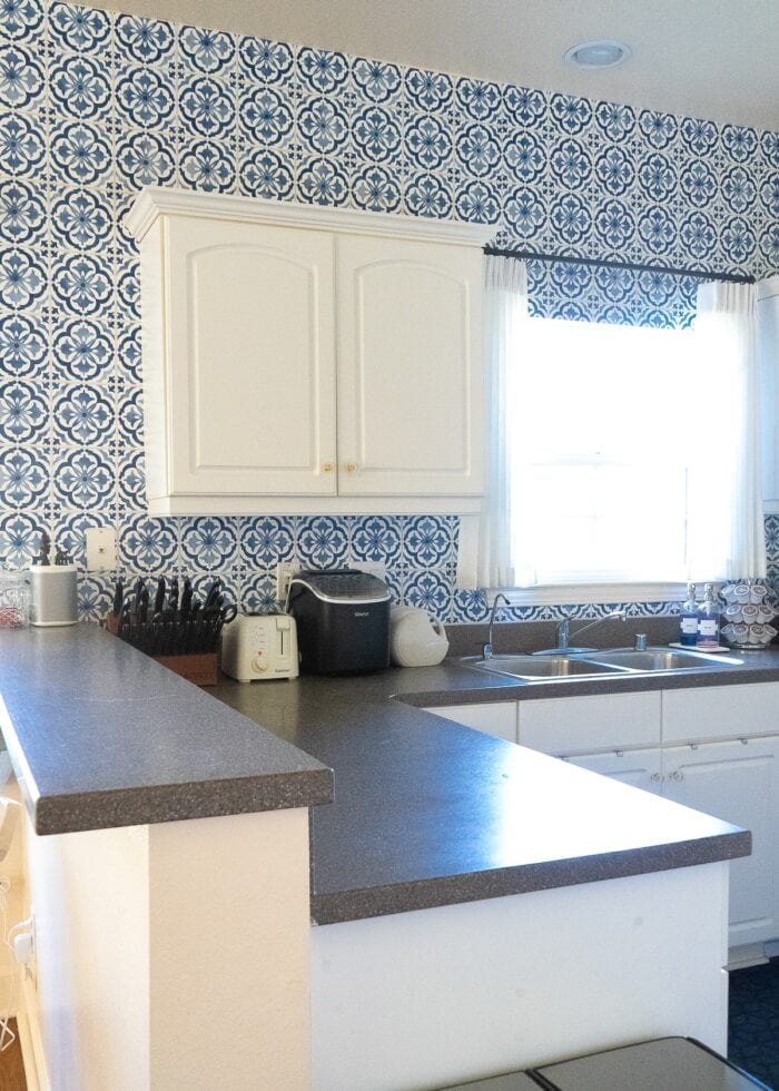 Small white kitchen with blue and white "tile" backsplash done with wallpaper