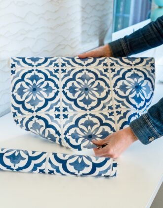 Megan unrolling a roll of blue and white tile backsplash wallpaper