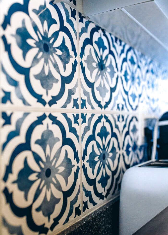 A kitchen backsplash covered in blue and white tile wallpaper