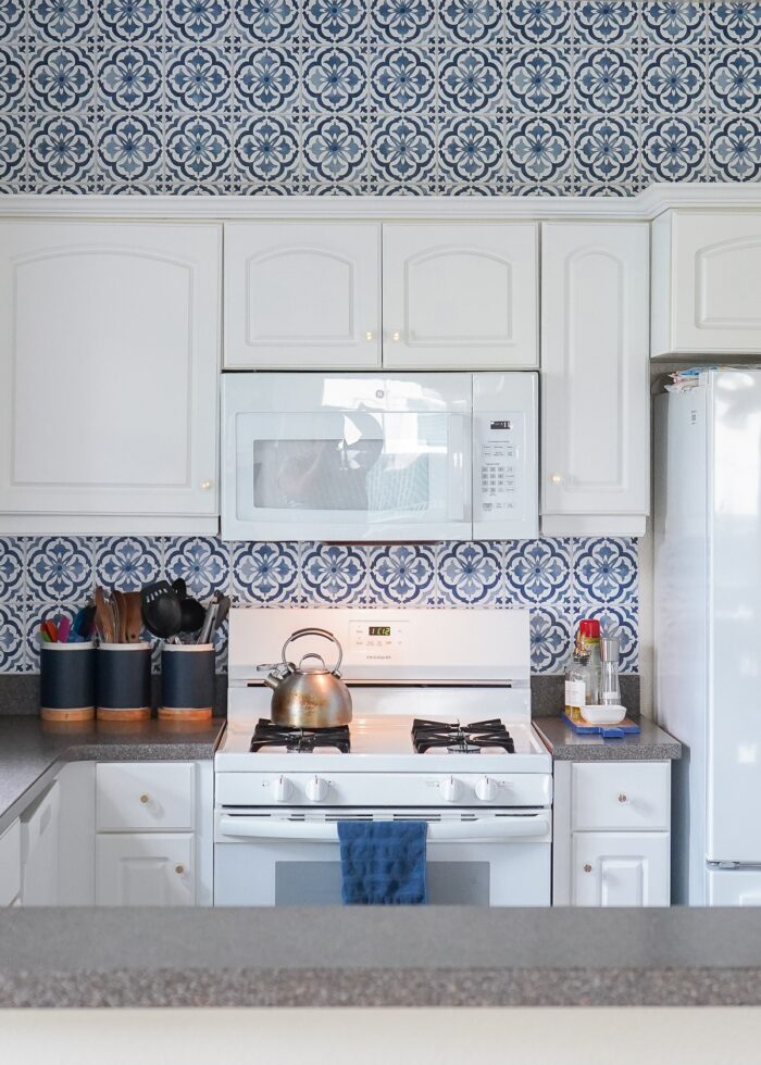 Small white kitchen with blue and white "tile" backsplash done with wallpaper