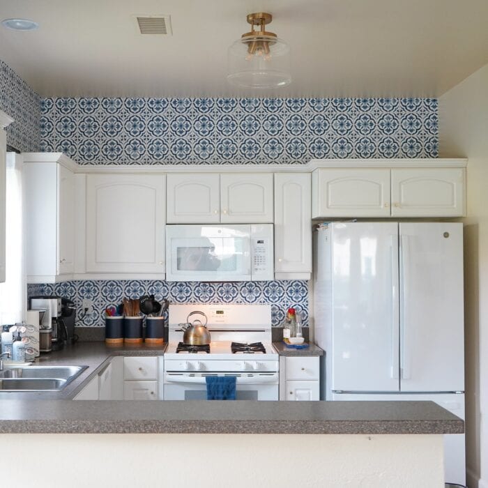 Small white kitchen with blue and white "tile" backsplash done with wallpaper
