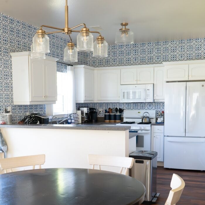 Small white kitchen with blue and white "tile" backsplash done with wallpaper