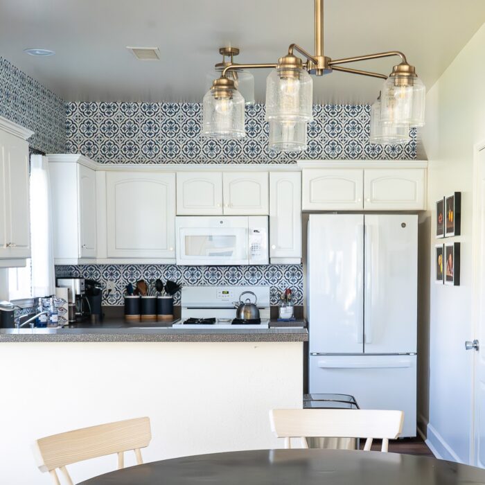 Small white kitchen with blue and white "tile" backsplash done with wallpaper