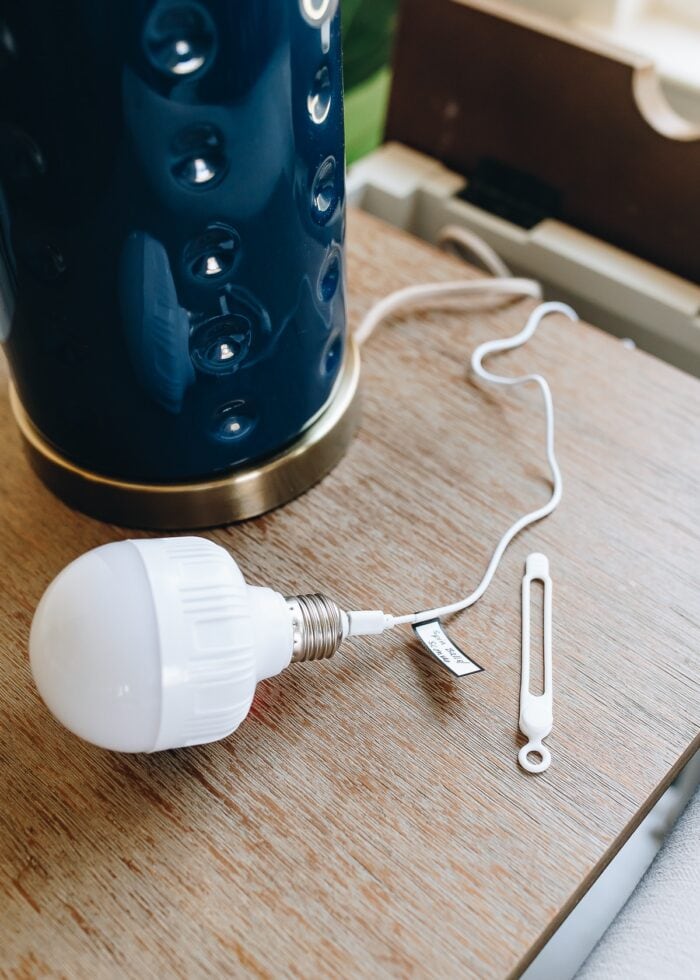 A rechargeable light bulb shown plugged in to a side table charging station