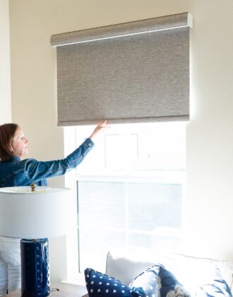 Megan pulling down on a brown blackout roller shade