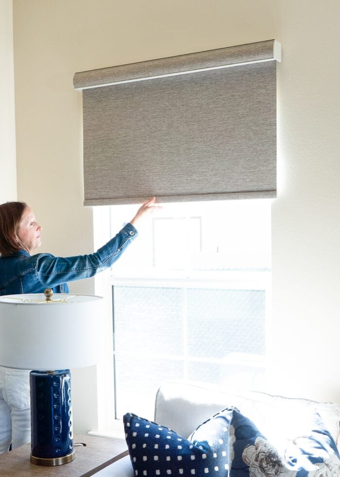Megan pulling down on a brown blackout roller shade