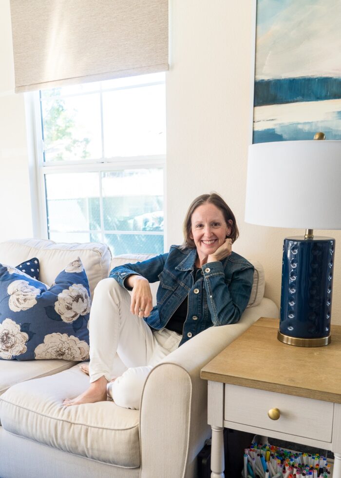 Megan sitting on a couch in front of a window with a brown textured black out roller shade