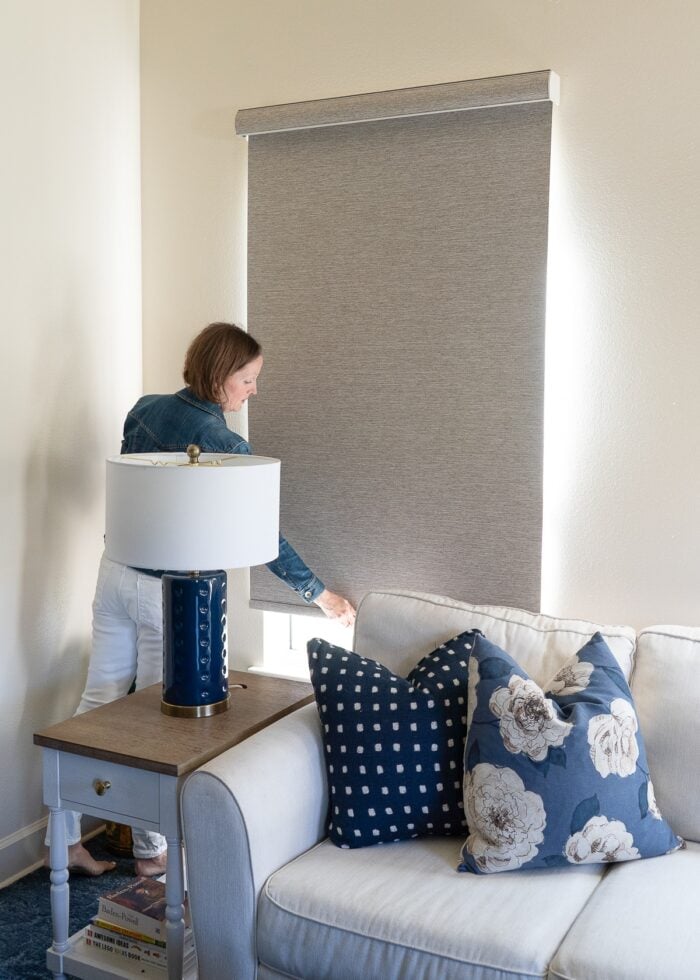Megan pulling down on a brown blackout roller shade