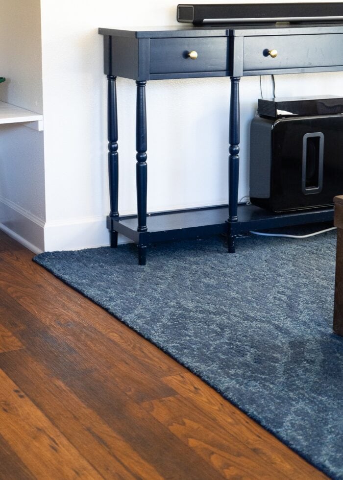 A corner shot of a re-bound blue wool rug in a family room