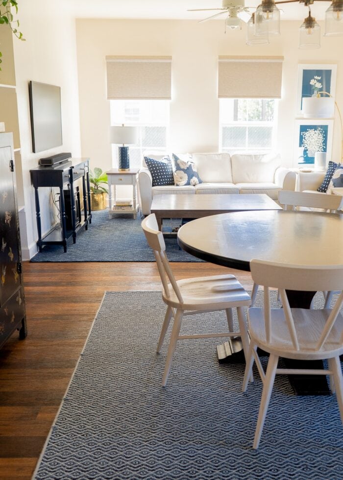 A combined family room and dining room featuring two rugs that were both re-bound