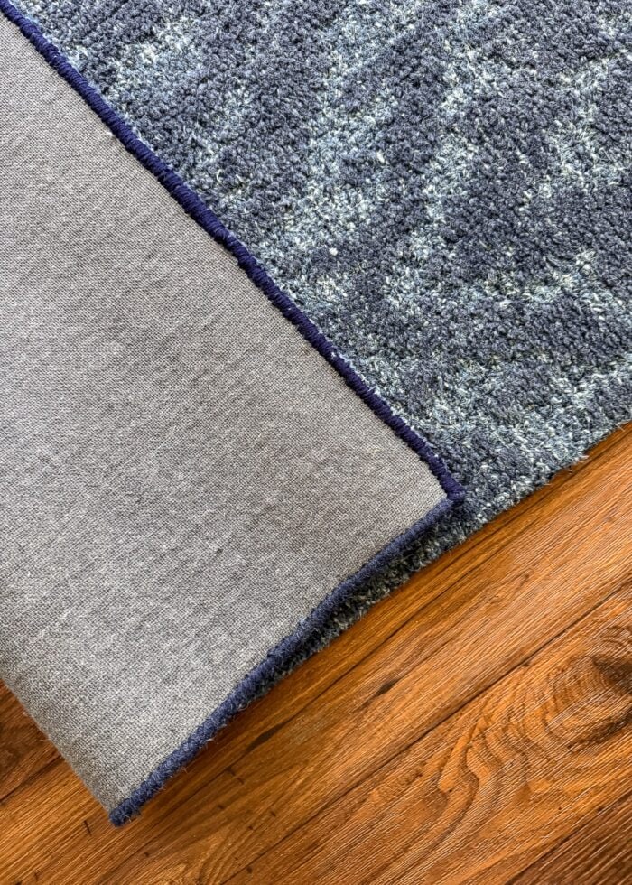 The under-side of a wool rug showing new and old hand binding