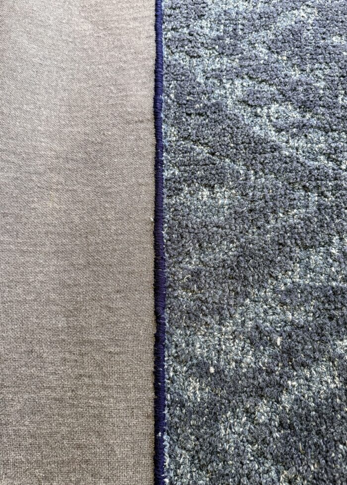 The under-side of a wool rug showing new hand binding