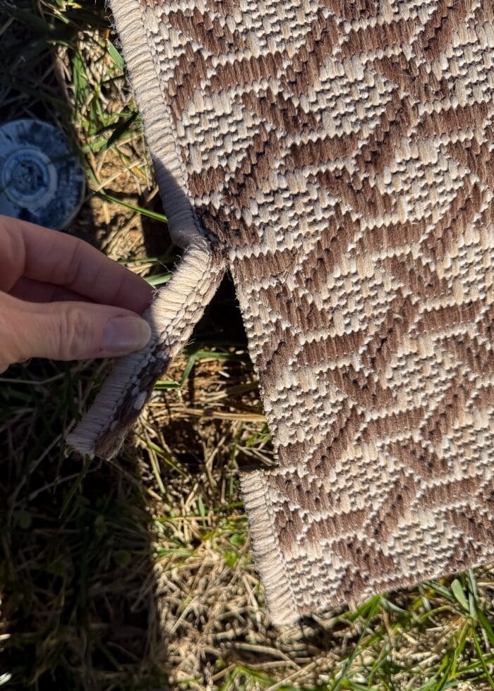 Hand showing an outdoor rug cut with scissors