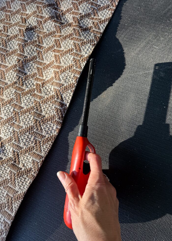 A hand holding a lighter right next to an outdoor rug
