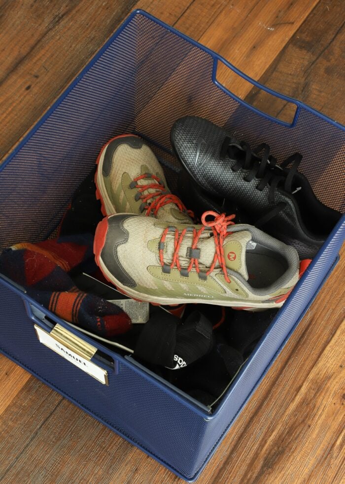 A blue metal basket full of shoes and socks