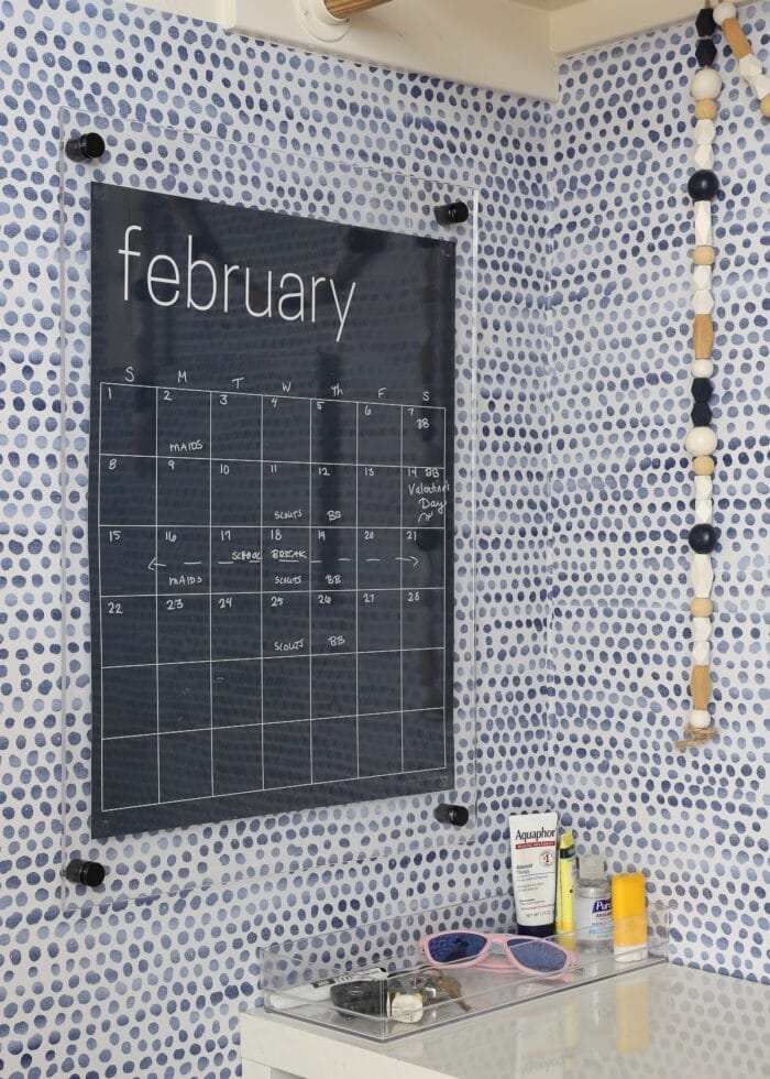 A dry-erase calendar hung on a wall in a mini mudroom