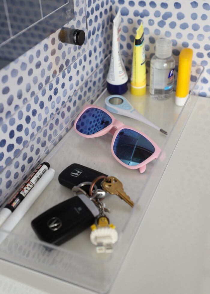 A tray holding keys, sunglasses, sunscreen, markers, and more.