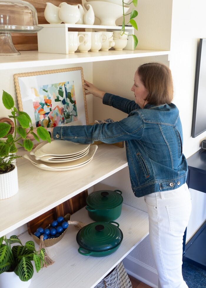 Megan from The Homes I Have Made placing a frame in the back of some deep floating shelves inside a nook.