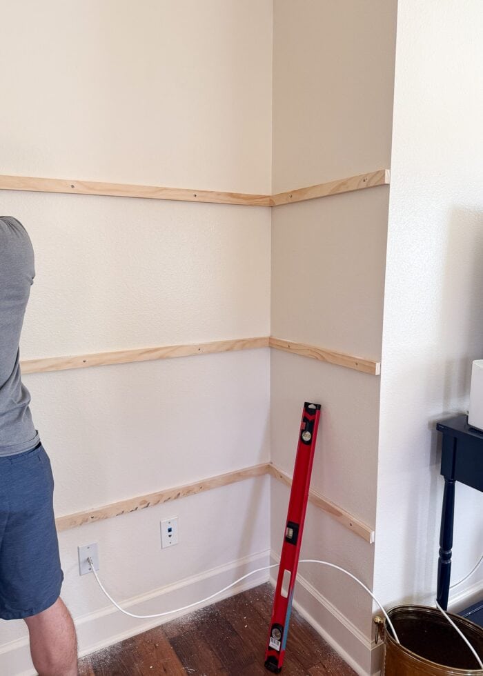Wood 1x2s drilled into a wall nook at equal intervals