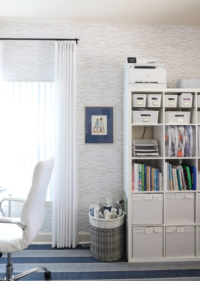 A craft room wall featuring an IKEA Kallax and a plastic hamper holding rolls of paper