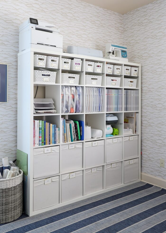 A 5x5 IKEA Kallax shelf filled with various bins, baskets, and cases holding a wide variety of craft supplies