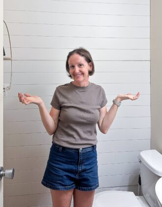 Megan in front of a white shiplap bathroom wall