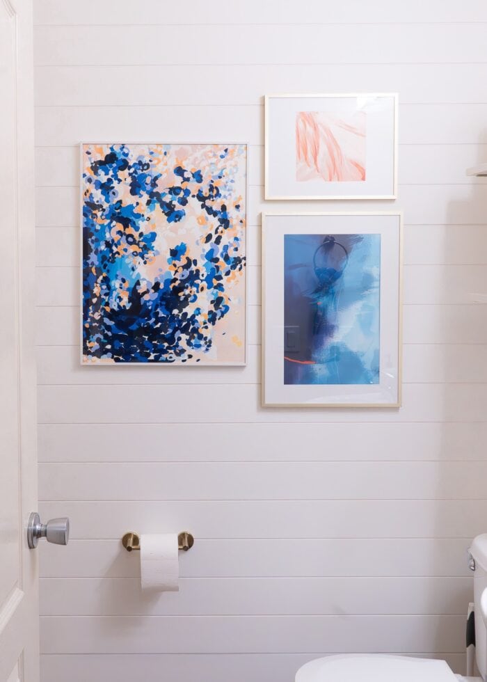 White shiplap wall paneling hung on a bathroom feature wall with artwork hung on top