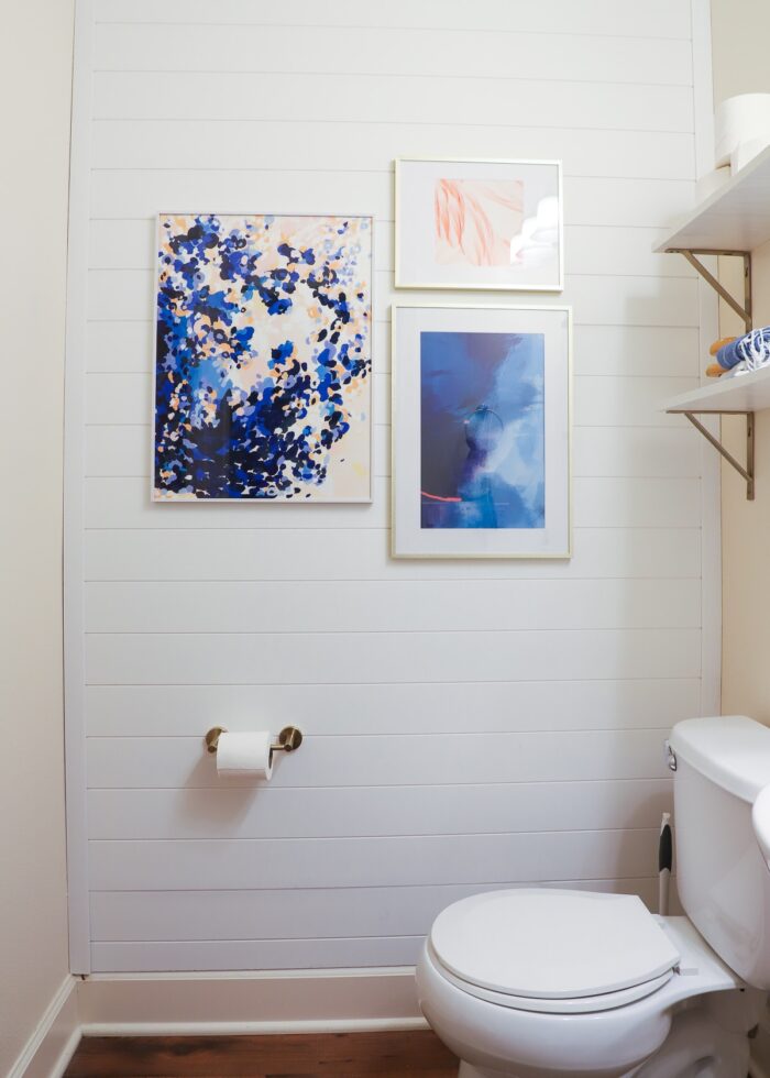 White shiplap wall paneling hung on a bathroom feature wall with artwork hung on top
