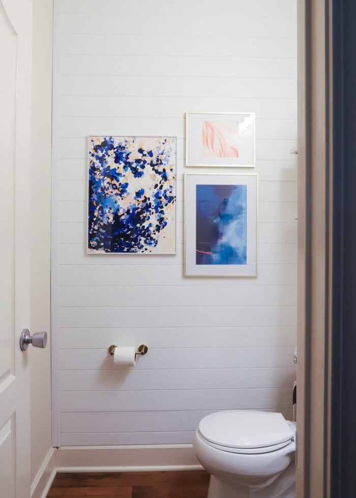 White shiplap wall paneling hung on a bathroom feature wall with artwork hung on top