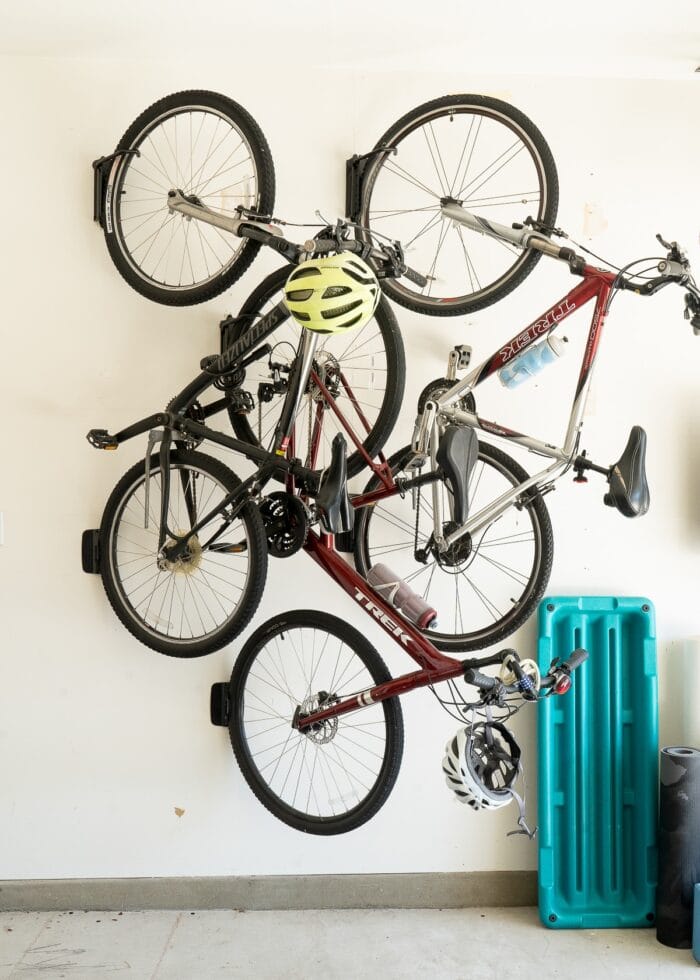 3 adult bikes mounted on swivel hooks on a garage wall