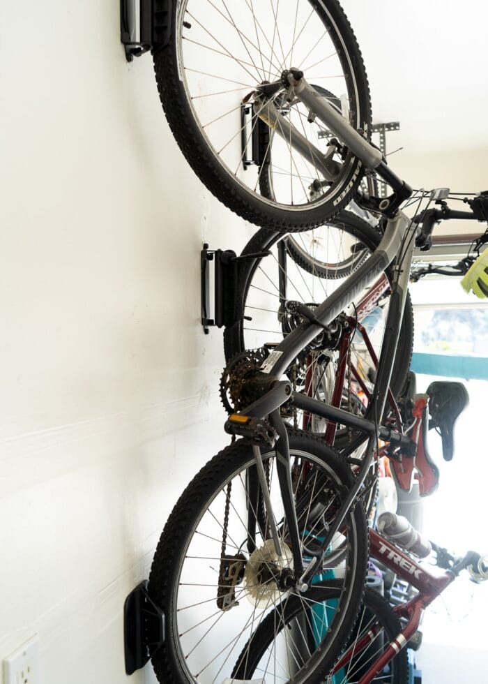 3 adult bikes mounted on swivel hooks on a garage wall