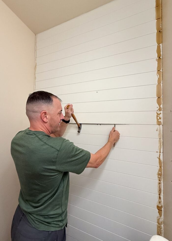 Greg removing shiplap from a bathroom wall