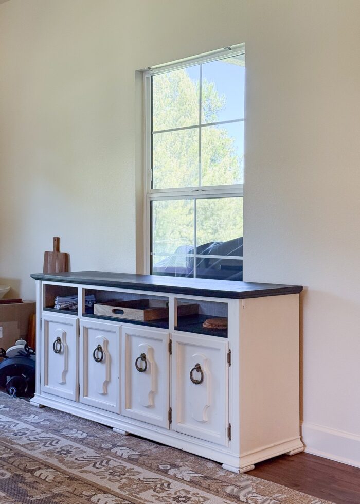 The bottom half of a dining hutch in front of a window