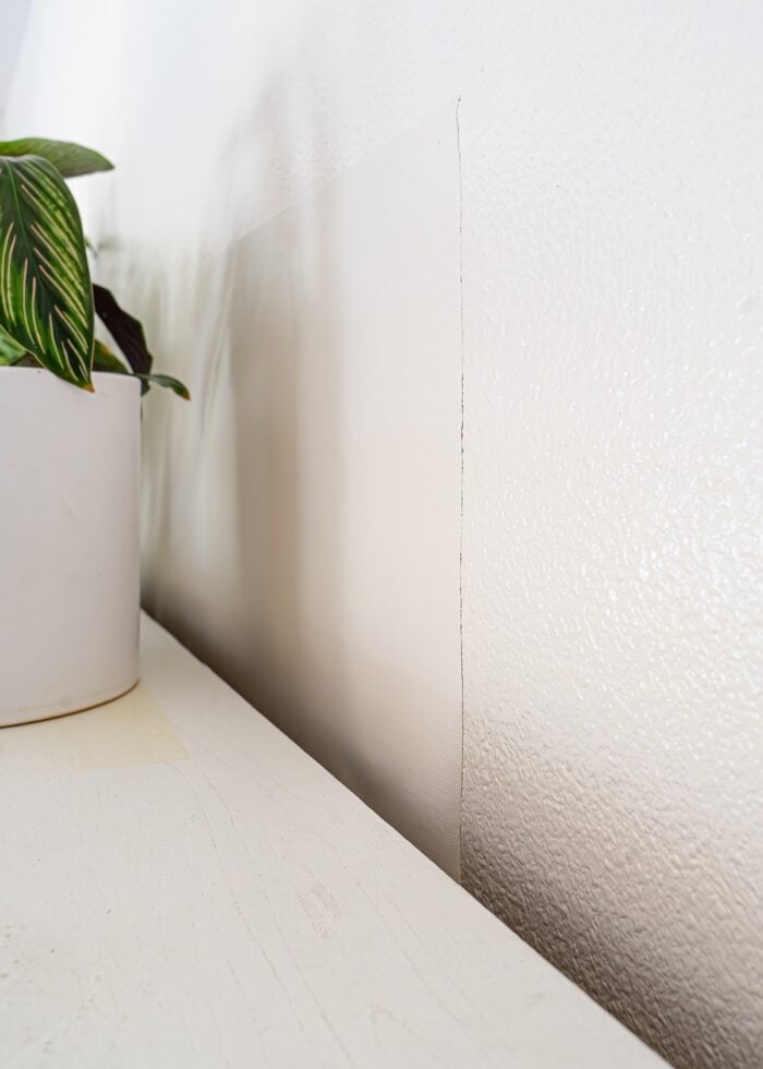 A wallpaper patch covering a window behind a white dining hutch