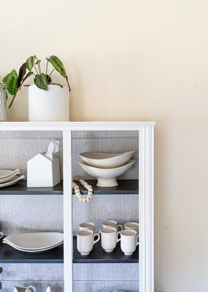 A wallpaper patch covering a window behind a white dining hutch