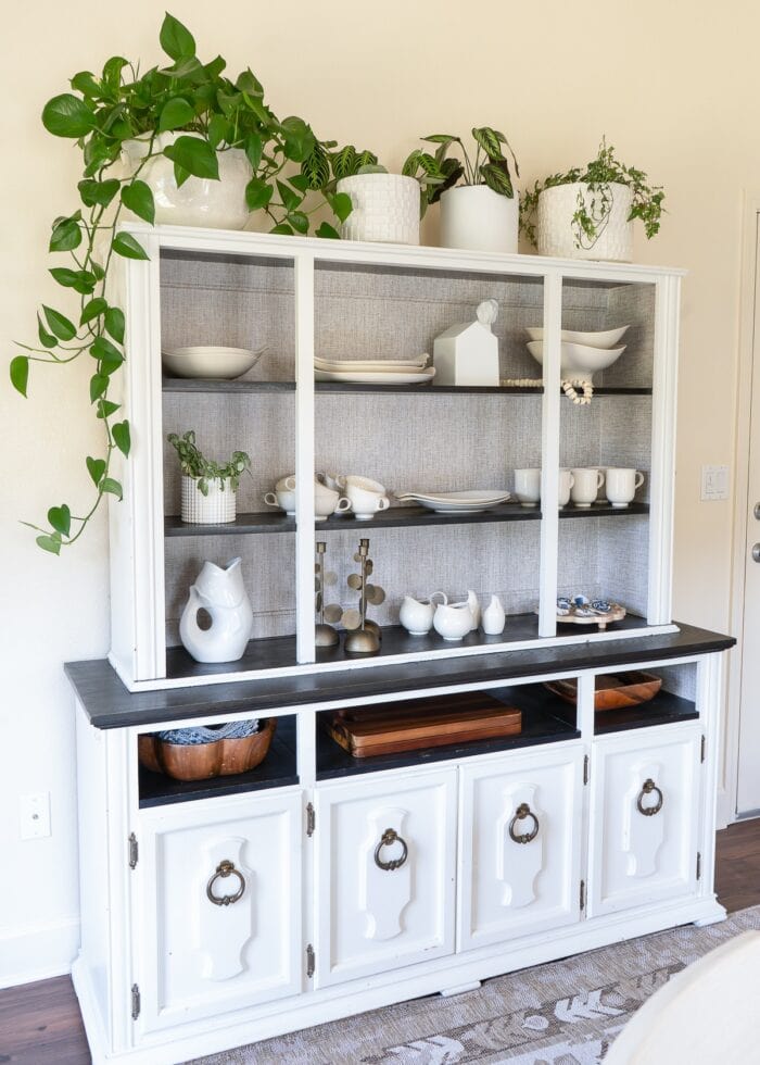 A white dining hutch covering up a window on a cream wall