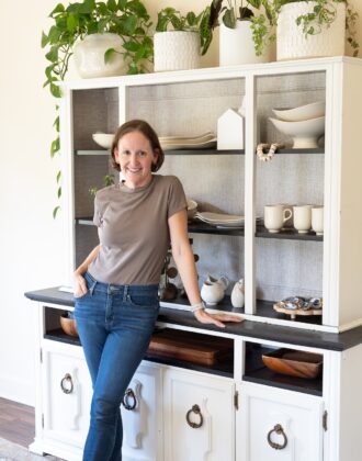 Megan in front of a white dining hutch