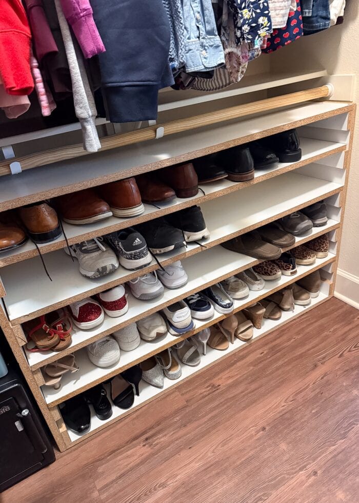 A basic shoe storage shelf on the closet floor underneath the lower hanging rod