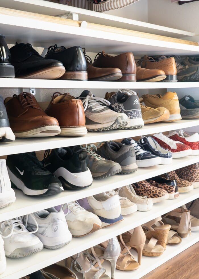 A DIY shoe shelf holding lots of pairs of shoes in a neat, color-sorted, organized arrangement