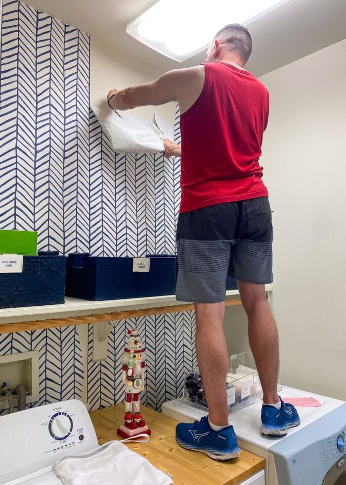 Man pulling off peel and stick wallpaper from the wall