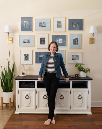 Megan in front of a white cabinet and blue and white frames