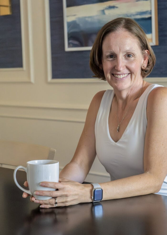 Megan sitting at a dining room table with a cup of coffee