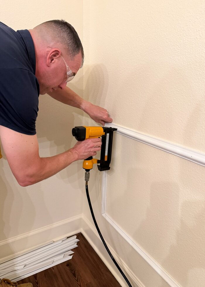 Greg using a nail gun to secure trim to a rental wall