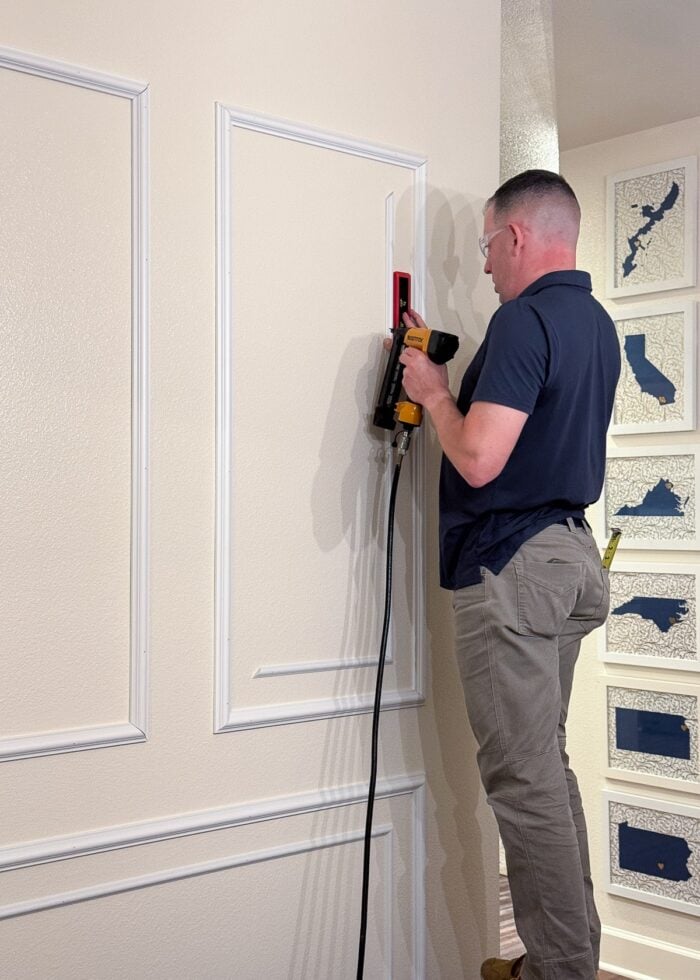 Greg using a nail gun and level to secure a trim frame to a rental wall