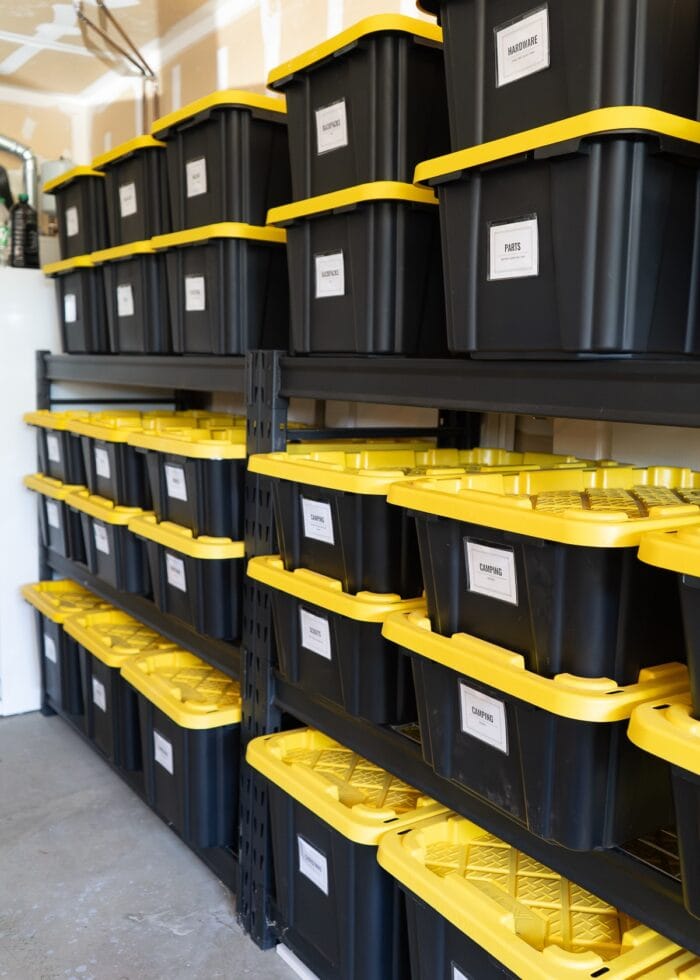Black shelves in a garage filled with different sizes of black and yellow HDX bins.