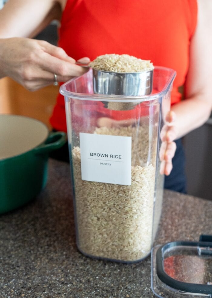 Megan from The Homes I Have Made scooping brown rice out of Rubbermaid Brilliance Pantry Canisters