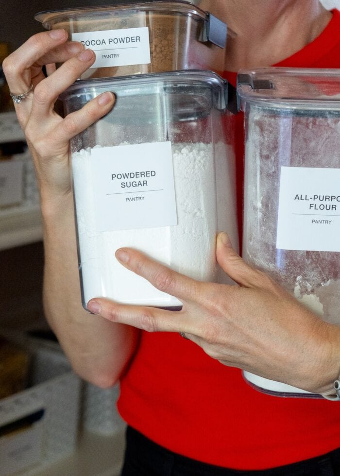 Megan from The Homes I Have Made holding Rubbermaid Brilliance Pantry Canisters near a pantry