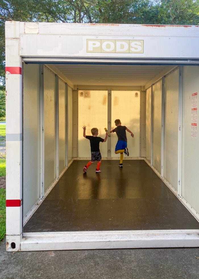 Two young boys dancing around the inside of a PODS storage unit